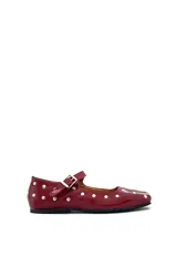 Zapato tipo Mary Jane color cereza charolado, con tachas plateadas, correa con hebilla y suela plana.