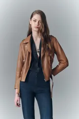 Campera estilo biker de cuero ovino color suela, con solapas, charreteras en los hombros, cinturón ajustable en la cintura y detalles de cierres metálicos.