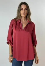 Blusa manga 3/4 color ladrillo, de seda, con cuello tipo camisa y detalle de cierre dorado en el escote.