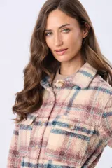 Campera tipo sobrecamisa de sherpa a cuadros en tonos beige, blanco, rosa y gris. Tiene cuello camisero, cierre frontal con botones, bolsillos de parche en el pecho y corte recto.