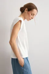 Remera mostaza de manga corta con detalles de encaje bordado (broderie) en los hombros, cuello redondo y corte recto.