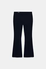 Pantalón de vestir azul marino, de tiro medio, con corte flare (campana) y pinzas frontales. Presenta cierre frontal oculto y bolsillos laterales.