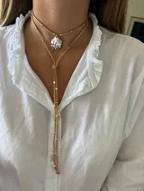 Collar de cuero azul con dije plateado en forma de caracol y detalles de cuentas plateadas. El collar tiene dos tiras que caen por el frente.