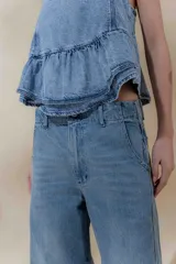 Pantalón de jean de tiro medio y pierna ancha, confeccionado en denim 100% algodón. Diseño con 5 bolsillos y pespuntes a contratono.