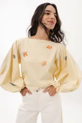 Blusa color crema con mangas largas abullonadas y escote a la base. Presenta bordados artesanales con motivos marinos distribuidos en el frente y las mangas.