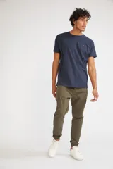 Pantalón cargo de corte slim, color verde oliva, con bolsillos laterales tipo cargo, cierre frontal con botón y puños elásticos en los tobillos.