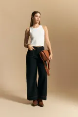 Jean de corte wide leg y tiro alto, color negro con costuras en contraste color ocre. Presenta bolsillos delanteros y traseros con detalle de pespunte, y ruedo ancho con costura decorativa.