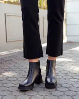 Botinetas de cuero negro con plataforma y taco cuadrado. Presentan un diseño combinado con una textura tipo reptil en la parte posterior y cierre lateral.