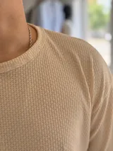Remera oversize de tejido de punto color beige, de manga corta y cuello redondo.