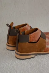 Zapato tipo botineta de cuero color bordó con textura grabada, diseño de punta fina y detalles de elásticos laterales en color negro.