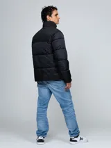 Campera puffer Tommy Hilfiger de color negro, con diseño acolchado, cuello alto y cierre frontal de cremallera. Cuenta con bolsillos laterales con cierre, el logo de la marca bordado en el pecho y un parche con el logo en la manga.