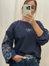 Buzo azul marino de algodón con cuello redondo, mangas globo con puño elastizado y detalle de bordado nórdico en la manga derecha. Incluye logo bordado en el pecho.