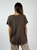 Blusa de satén color blanco, con cuello en V, mangas cortas y corte holgado con dobladillo asimétrico más largo en la parte posterior.