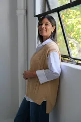 Chaleco de punto color beige, con cuello en V y diseño de trenzas verticales. Presenta un corte holgado y terminaciones acanaladas en el cuello, sisas y ruedo.