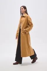 Trinchera larga de corte holgado, con cuello solapa, cierre frontal con botones y cinturón ajustable a la cintura. Cuenta con mangas largas y bolsillos laterales.