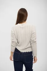 Saco de punto gris claro con textura acanalada, cuello redondo, cierre frontal con botones y bordes con terminación ondulada.