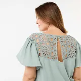 Camiseta color verde menta de tejido crepé con escote en V y mangas cortas acampanadas. Presenta detalles de encaje de macramé en los hombros.