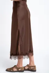 Falda midi negra de acabado satinado, corte al bies, con detalle de encaje en el ruedo.