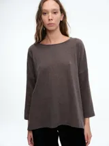 Buzo tejido de silueta relajada con sisa caída y tajos laterales que aportan movimiento. Presenta cuello redondo y mangas tres cuartos.