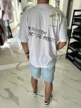 Remera blanca oversize con estampado gráfico en negro y verde en la espalda, de manga corta y corte holgado.