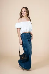 Blusa blanca con escote elástico que permite usarla con hombros descubiertos o más alta.