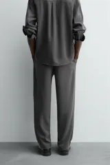 Pantalón de corte relaxed fit, con cintura ajustable, bolsillos delanteros y bolsillo trasero de plastrón. Presenta cierre frontal con cremallera y botón.