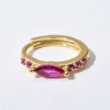 Aro huggie dorado con dije de cristal fucsia en forma de ojo de marquesa y pequeños cristales fucsias engarzados.