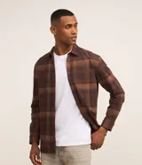 Camisa de corte regular para hombre, confeccionada en algodón con estampa a cuadros en tonos marrones. Cuenta con cuello camisero, cierre frontal con botones, mangas largas y un bolsillo aplicado en el pecho con detalle de botón.