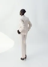 Pantalón de vestir de lino color beige, de corte recto y tiro medio, con trabillas, bolsillos laterales y bolsillos posteriores de ribete.