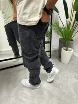 Pantalón cargo de jean con efecto gastado, corte baggy oversize, con bolsillos laterales tipo cargo y cierre frontal.