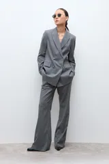 Blazer de corte sastre con doble botonadura frontal, solapas clásicas y bolsillos laterales con solapa. Presenta un diseño estructurado con estampado de microcuadros.