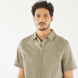 Camisa de manga corta color verde oliva con cuello clásico y cierre abotonado. Presenta un sutil estampado floral bordado en toda la prenda.