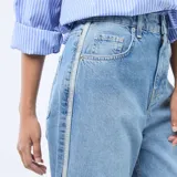 Pantalón de jean estilo baggy con tiro bajo, corte amplio y pierna recta. Presenta un lavado azul medio con costuras laterales destacadas en tono claro.