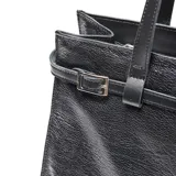 Cartera shopper de cuero negro con textura granulada, doble asa de hombro y detalles de tiras con hebillas metálicas. Cuenta con el logo de la marca en aplique metálico frontal.