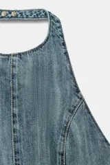 Mono corto de denim con cuello halter, espalda descubierta y costuras marcadas.