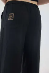 Pantalón de lino color beige, de silueta relajada, tiro medio-alto, cintura elastizada con cordón ajustable, bolsillos laterales y bolsillos traseros.