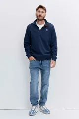 Pantalón de jean corte regular, color azul medio con efecto lavado, de tiro medio y cierre frontal con botón y cremallera.