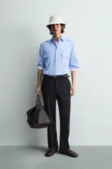 Camisa de algodón color celeste, corte relaxed fit, con cuello solapa, manga larga y trabillas en los hombros. Presenta dos bolsillos de plastrón con solapa en el pecho.