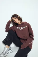 Canguro negro de silueta relajada con capucha, bolsillo canguro y estampados gráficos blancos en el pecho y las mangas.