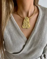 Collar rígido dorado con dije rectangular irregular con textura rugosa.