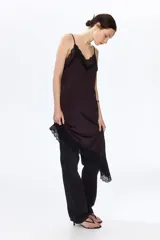Vestido midi de punto interlock con ribete de encaje negro en el escote y bajo asimétrico. Tiene breteles spaghetti y escote en V.