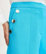 Bermuda de corte sastrero confeccionada en crepé color turquesa, con cierre frontal, bolsillos laterales y detalle de botones decorativos en los costados.