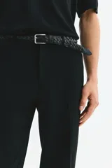 Pantalón sastrero de corte ajustado, color negro, con pliegues frontales, cierre de botón, bolsillos laterales y bolsillos traseros ribeteados.