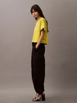 Remera corta color amarillo con cuello redondo, mangas cortas y bolsillo en el pecho con escudo bordado en blanco.
