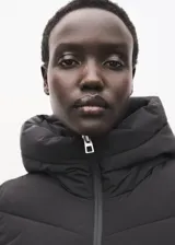 Campera acolchada tipo puffer color negro, con capucha, cuello alto y cierre frontal de cremallera doble. Presenta diseño recto, mangas largas con puños elásticos y bolsillos laterales con cierre.