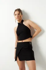 Minifalda negra de corte asimétrico con hebilla metálica.