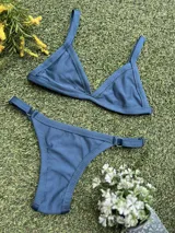 Conjunto de bikini color petróleo, de lycra acanalada, compuesto por un corpiño de triángulo fijo con breteles regulables y una bombacha colaless regulable con argollas metálicas.