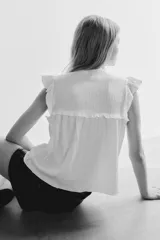 Top blanco de manga corta con escote redondo y abertura en V con tiras para atar. Presenta canesú con inserciones de encaje y costura fruncida con volados. Corte holgado.