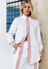 Camisa de lino blanca de corte relajado, con cuello camisero, manga larga y detalles a rayas rojas en la botonera frontal, los puños y los hombros.