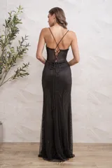 Vestido largo de fiesta color negro, con escote corazón y cuerpo tipo corset con transparencias y detalles brillantes. Presenta breteles finos, falda con tajo lateral profundo y tejido de red con acabado brillante.